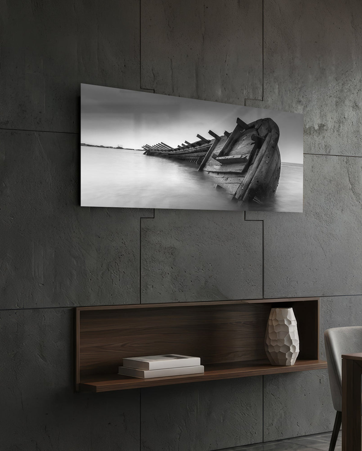 Black and white shipwreck glass wall art above a dark wood wall shelf on a charcoal paneled wall