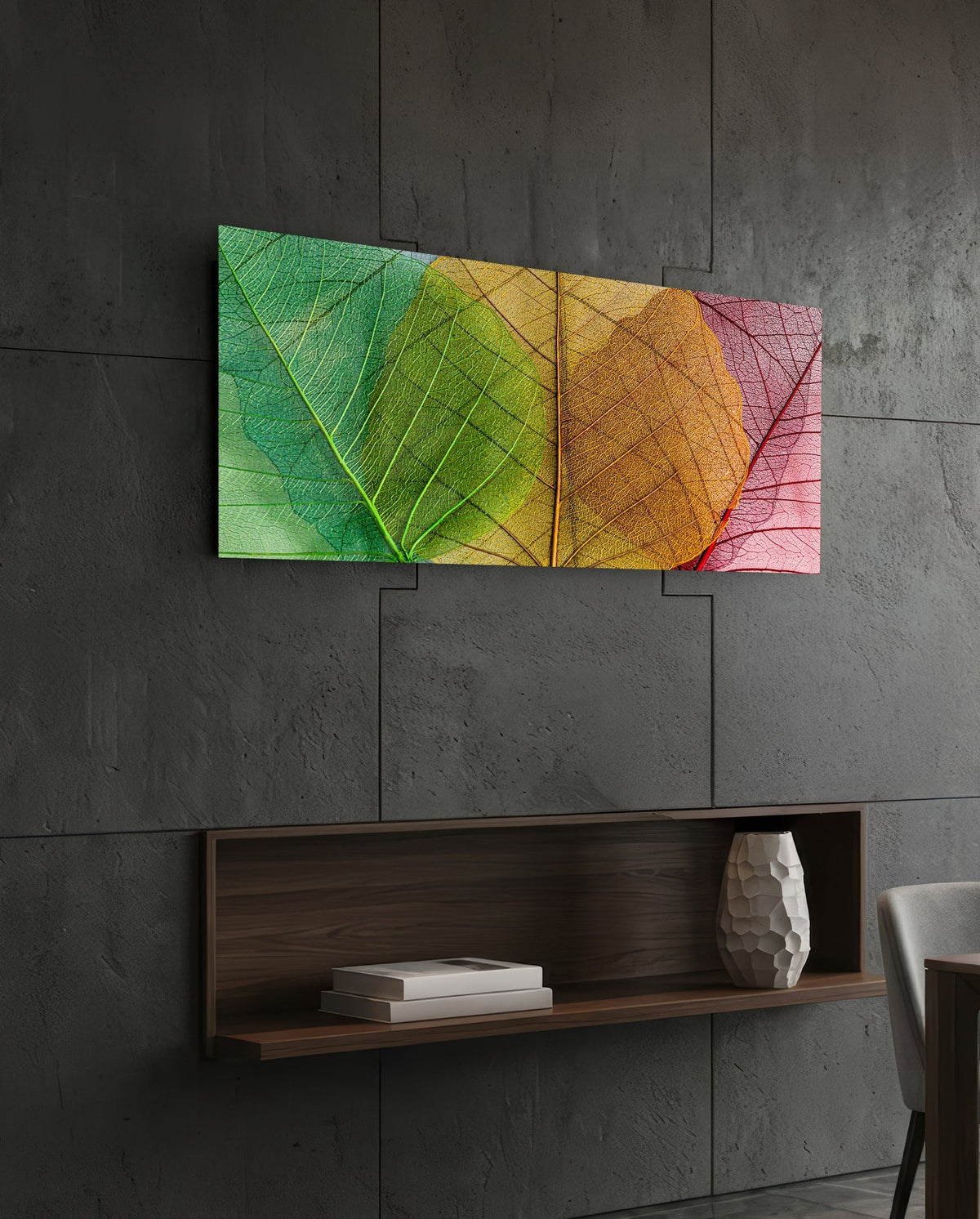 Green to pink veined leaves glass wall art on a dark slate wall above a walnut floating shelf