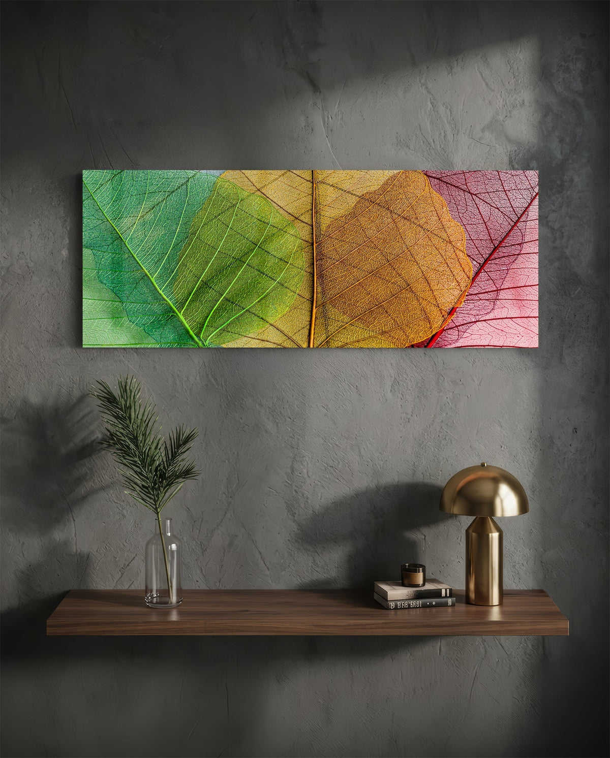 Green to pink veined leaves glass wall art above a floating shelf with a brass lamp and a plant in a vase