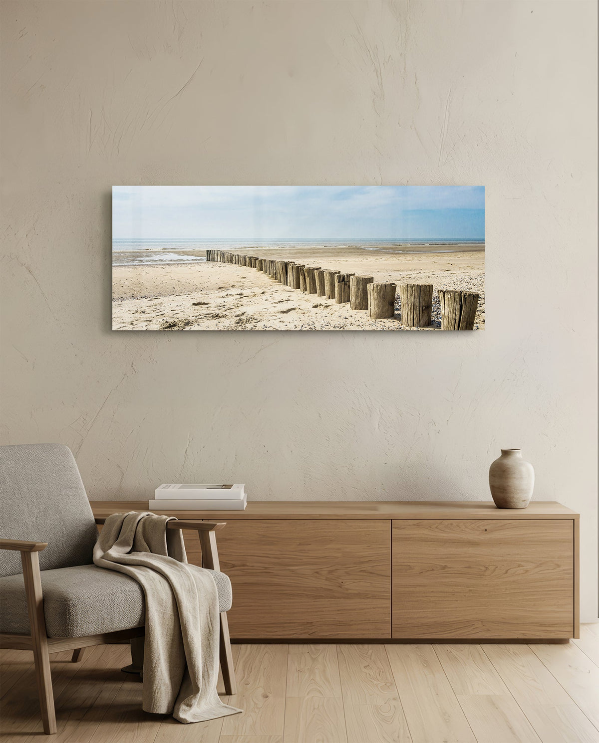 Weathered wood posts on the beach glass wall art above a light oak sideboard beside a cream armchair