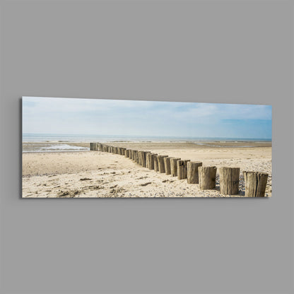 Weathered wood posts on the beach panoramic glass print angled on a gray background