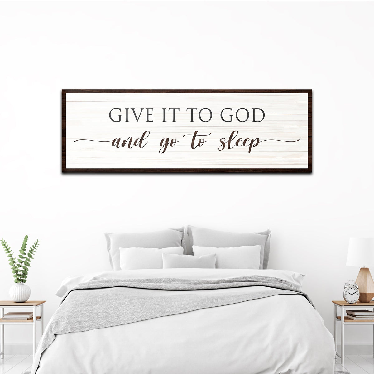 Long white plank-look canvas sign reading Give It To God in serif capitals and and go to sleep in script, above a bed