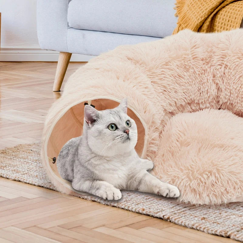 Beige plush cat tunnel bed with peekaboo cave design featuring a white cat resting inside