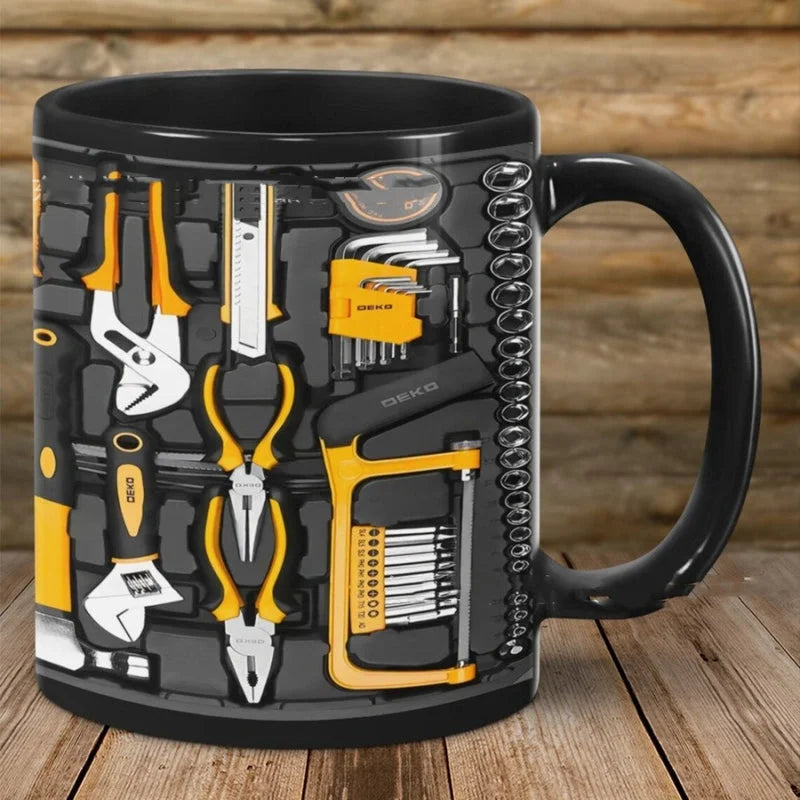 Black ceramic coffee mug with 3D toolbox design featuring yellow tools, wrenches, pliers and screwdrivers