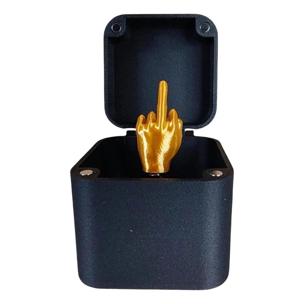 Black jewelry box with a gold middle finger ring inside on a white background