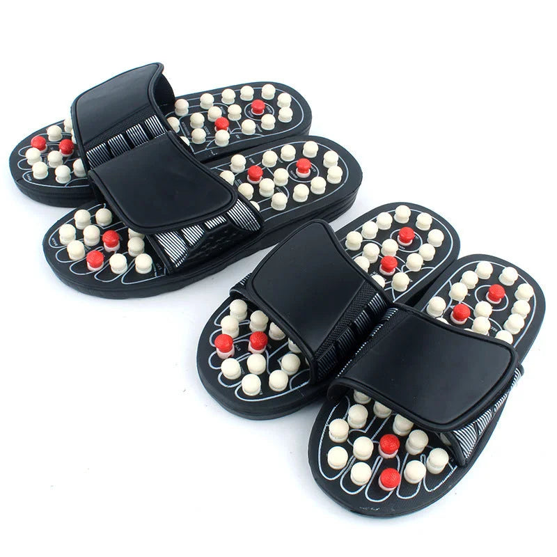 Black massage slippers worn while standing, showing full sole acupressure contact
