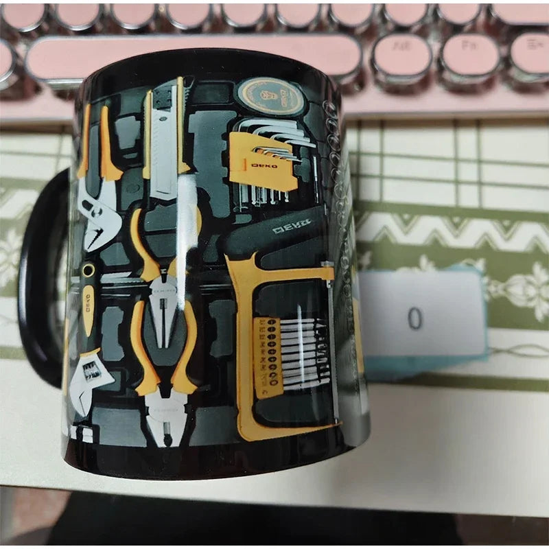 Black toolbox design coffee mug with yellow tools print on office desk next to laptop