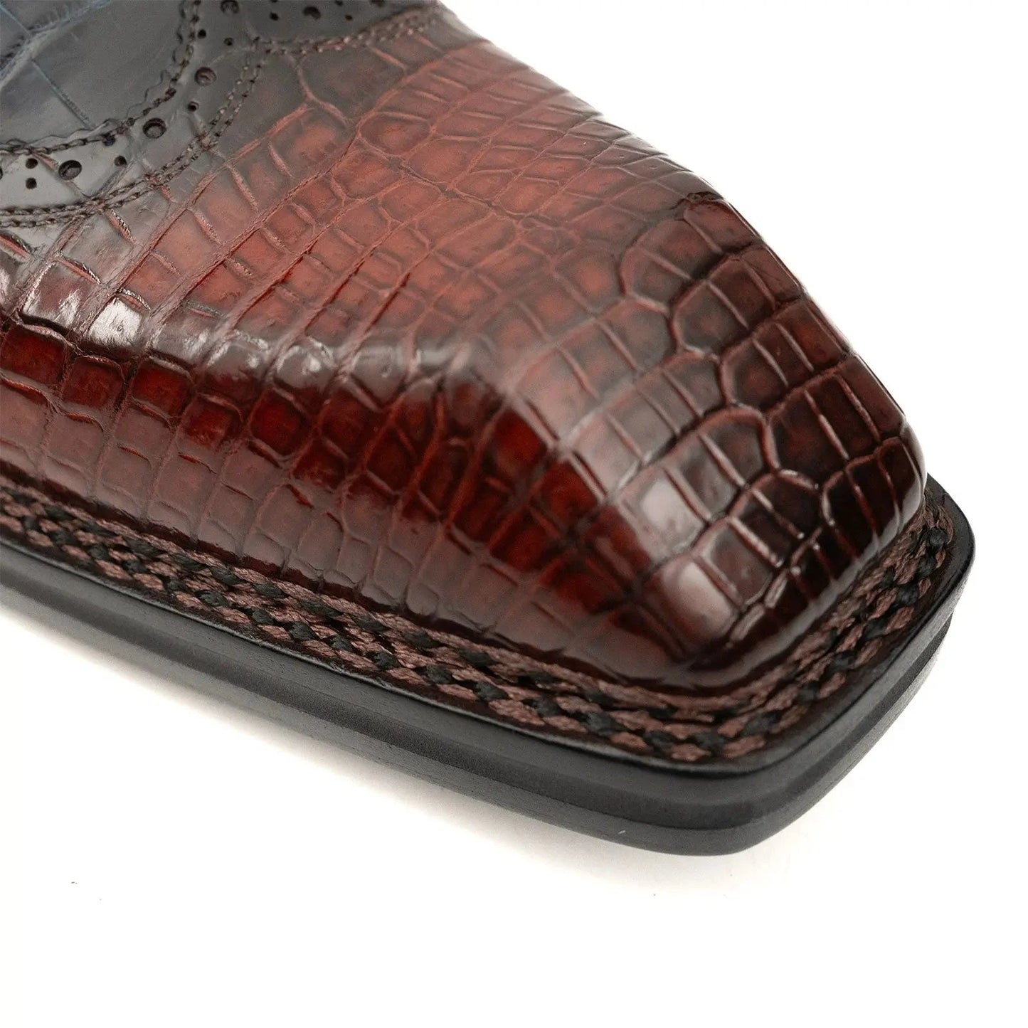 Close-up squared toe box crocodile leather shoes showing precision brogue perforations artisan craftsmanshipClose-up squared toe box crocodile leather shoes showing precision brogue perforations artisan craftsmanship