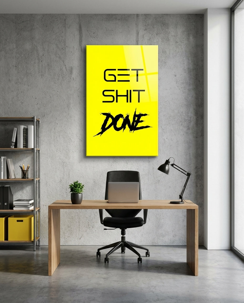 Get Sh*t Done black brush script on yellow glass wall art above a wood desk and black office chair