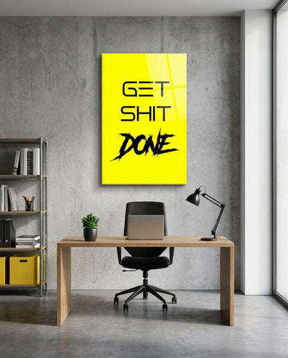Get Sh*t Done black brush script on yellow glass wall art above a wood desk and black office chair