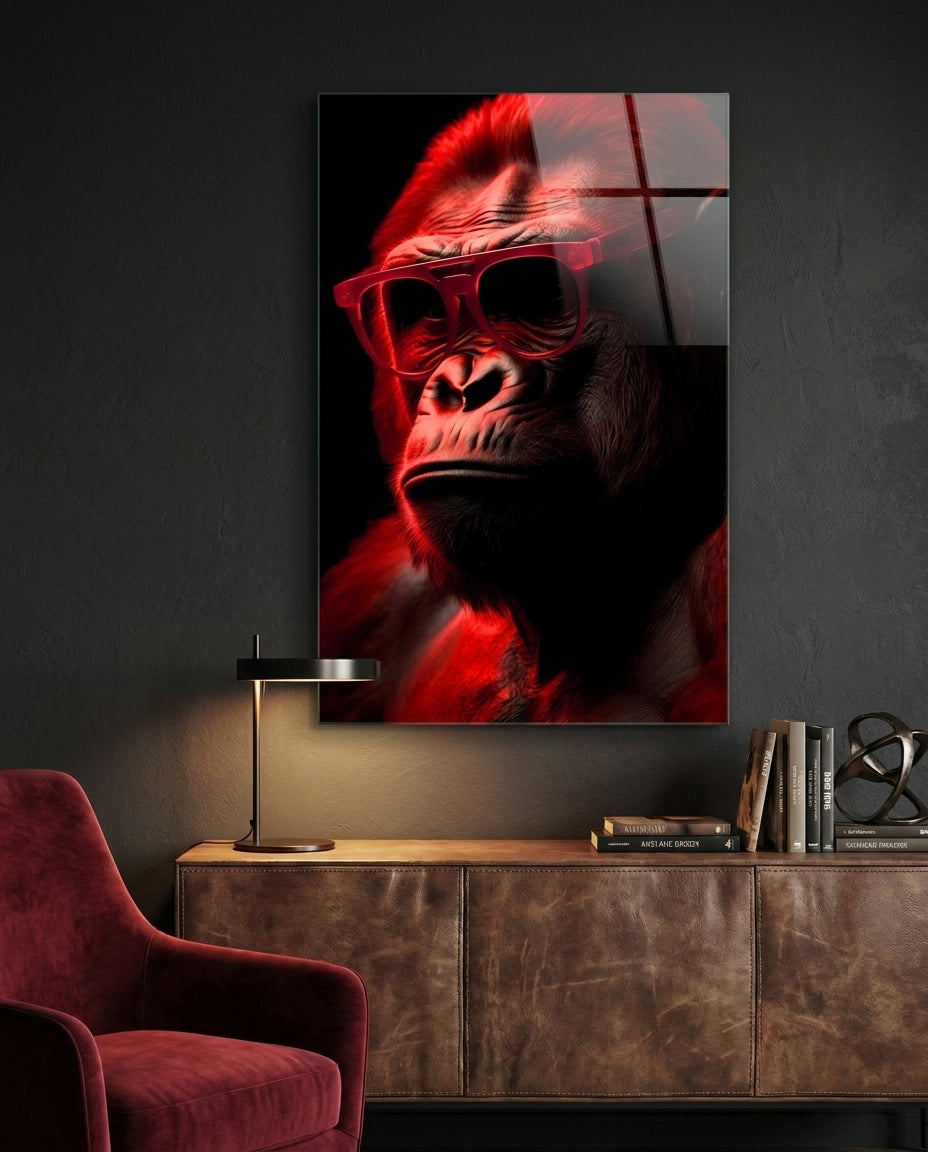 Red thinking gorilla in sunglasses glass wall art on a dark wall above a leather sideboard beside a red velvet armchair
