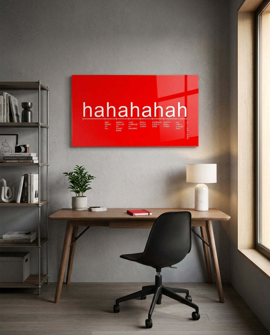 Red laughter scale typography glass wall art above a wood desk with a black office chair beside a window