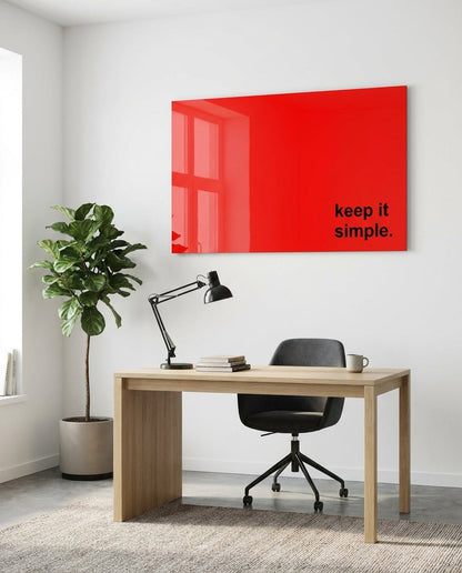 Keep it simple black text on red glass wall art above a wood desk beside a potted tree
