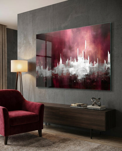 Crimson mist abstract skyline glass wall art above a dark sideboard beside a red velvet armchair