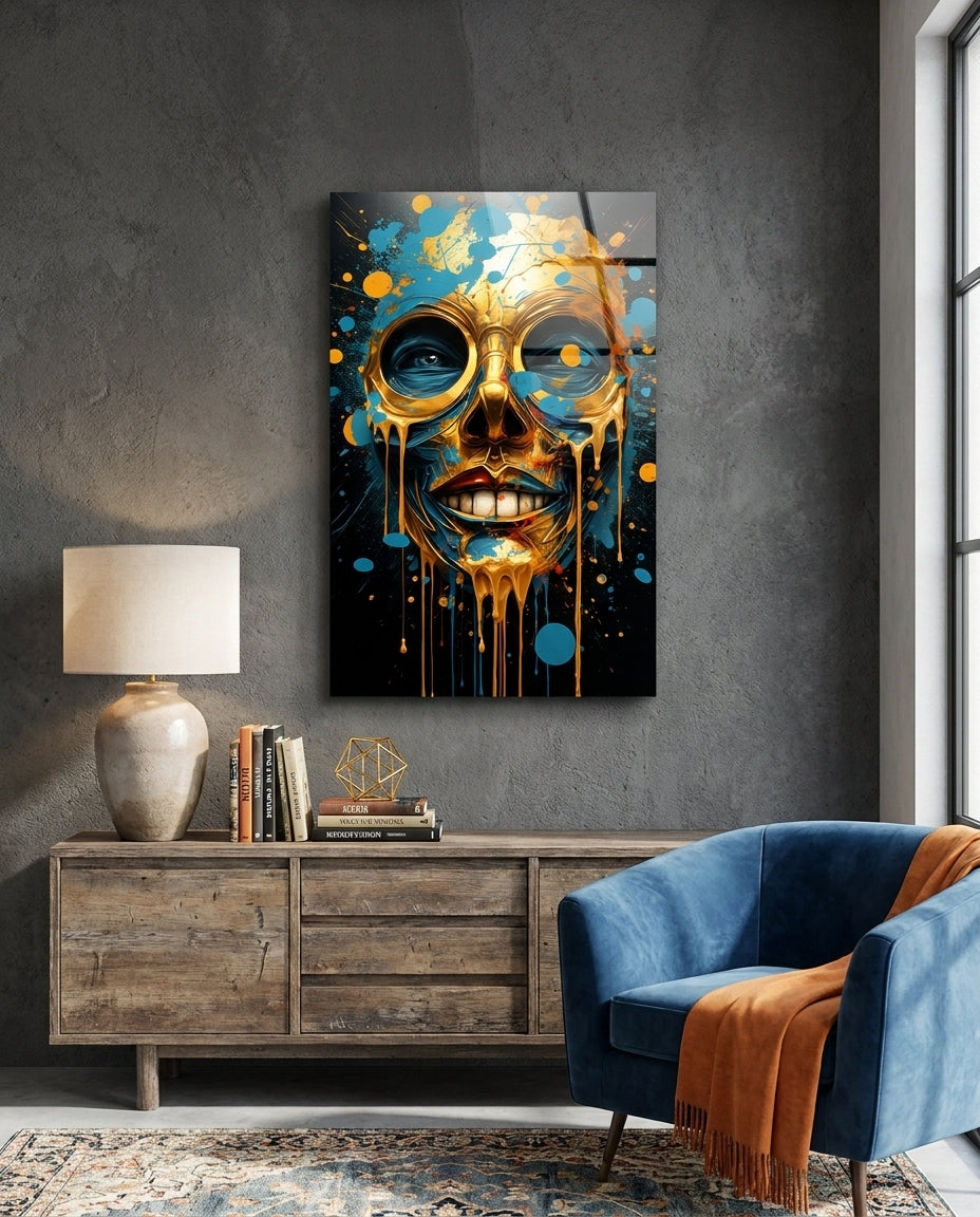 Gold drip mask face glass wall art above a wooden sideboard beside a blue armchair with an orange throw