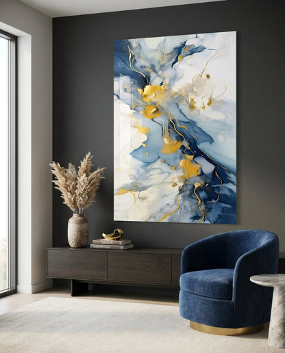 Indigo and gold marble glass wall art beside a navy swivel armchair and a dark console with dried grass