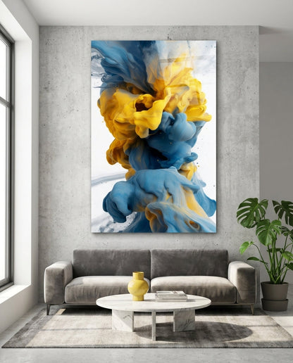Blue and yellow ink swirl abstract glass wall art above a gray sofa and round white coffee table on a concrete wall