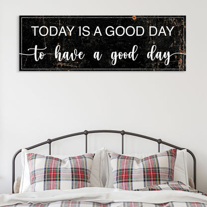 Today Is a Good Day canvas sign in the black style with white letters, above an iron bed with plaid pillows