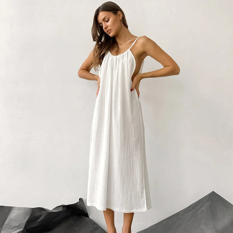Full-length view of white halter pajama dress featuring V-neck, adjustable straps, and flowing midi-length design
