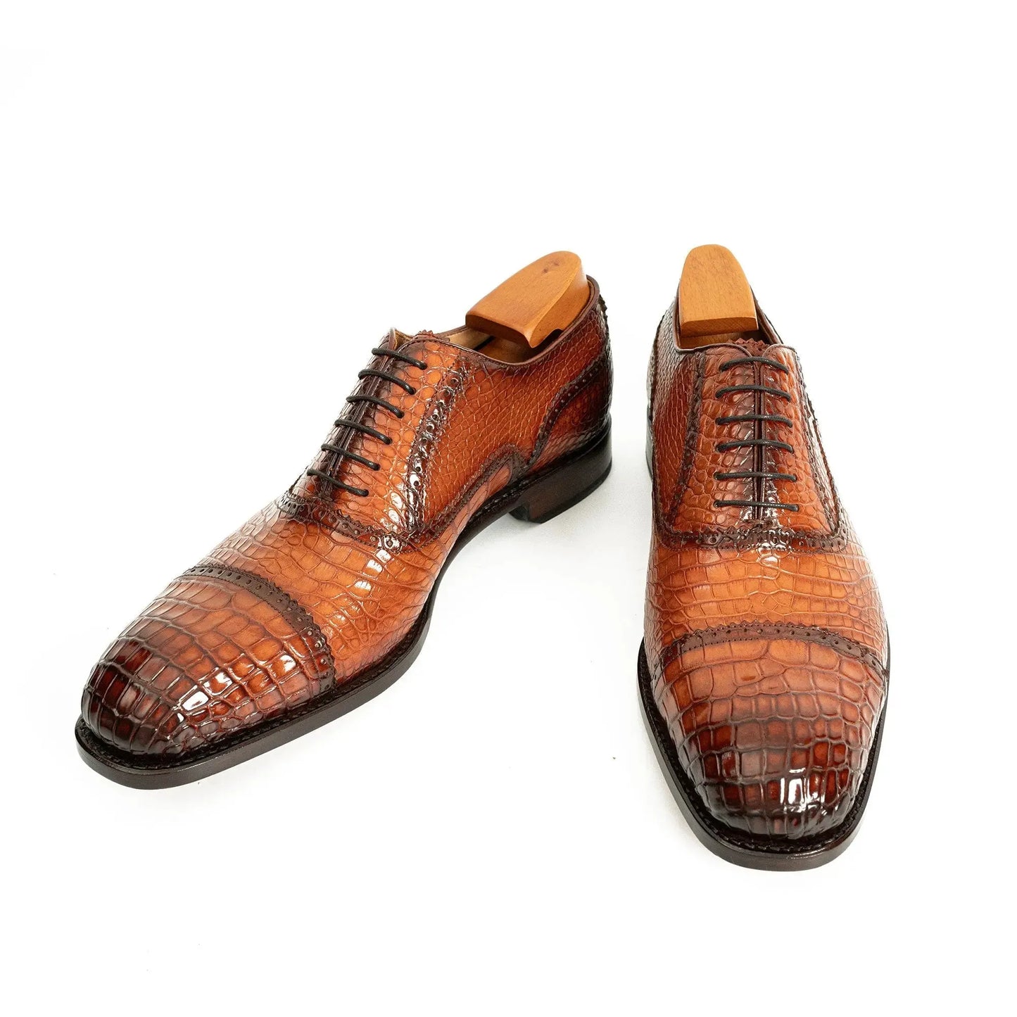 Glossy crocodile pattern on pair of luxury brown men's dress shoes