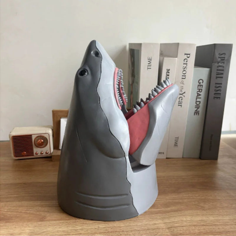 Gray shark snack holder with open jaws displaying pink interior and detailed tooth design on bookshelf