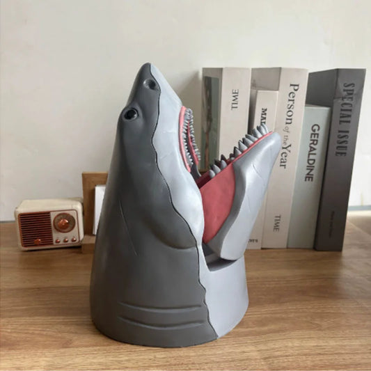 Gray shark snack holder with open jaws displaying pink interior and detailed tooth design on bookshelf