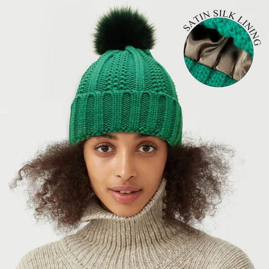 Green cable knit beanie with satin silk lining and faux fur pom pom for hair protection
