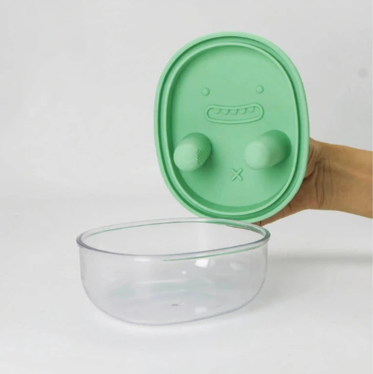 Green portable snack storage container showing button dispensing feature
