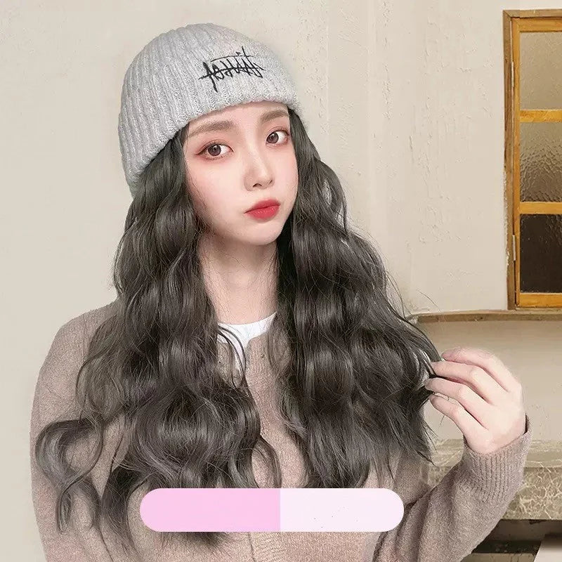 Grey knit cap with built-in long wavy wig styled with casual sweater showing natural hair integration