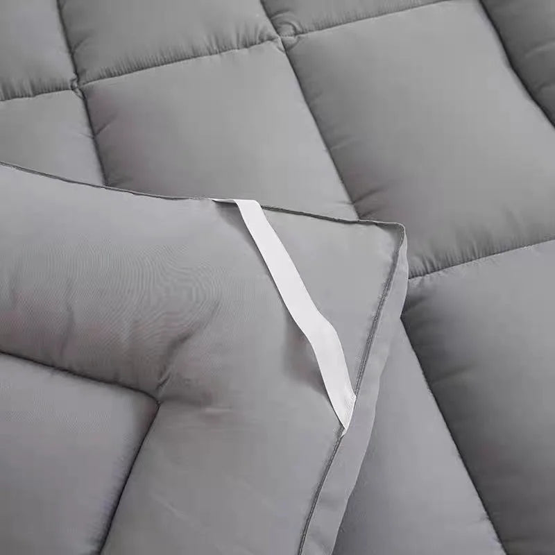 Grey mattress topper pad corner with elastic strap securing mattress