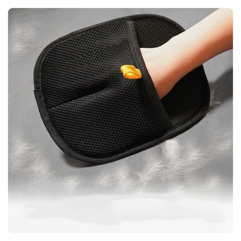 Hand brushing surface with black mesh pet hair removal glove collecting loose pet hair.
