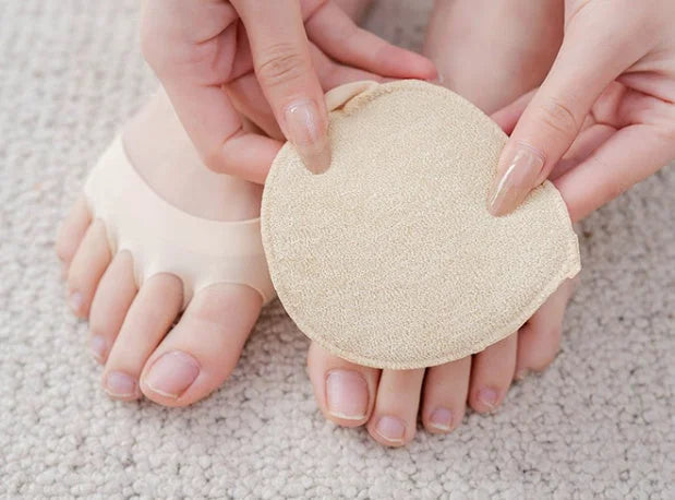 Hand holding beige forefoot cushion pad showing soft ice silk material and circular design
