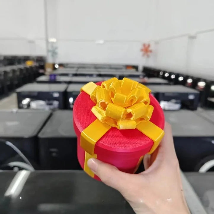 Hand holding red Christmas gift box with yellow bow - 3D printed matryoshka surprise decoration