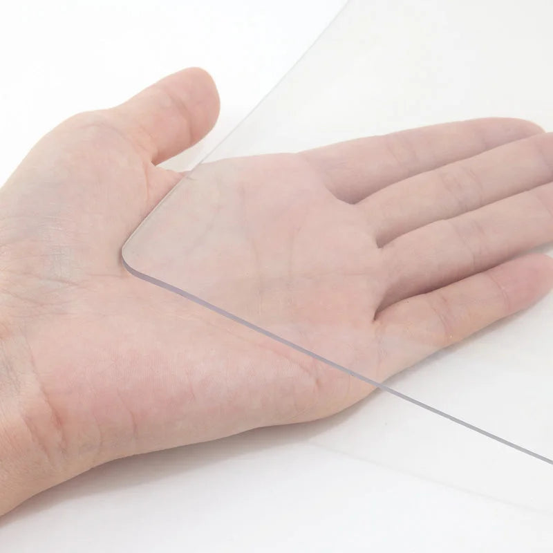 Hand holding transparent PVC table cover showing flexible thickness