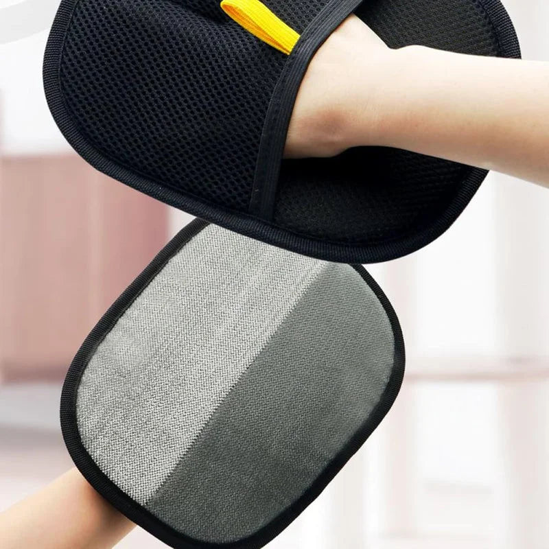 Hand wearing a black two-sided pet hair removal glove with mesh backing and grey electrostatic fabric front.