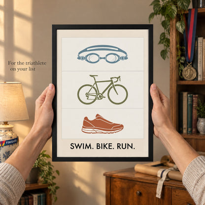 Hands holding out the framed triathlon print as a gift in a warm neutral living room