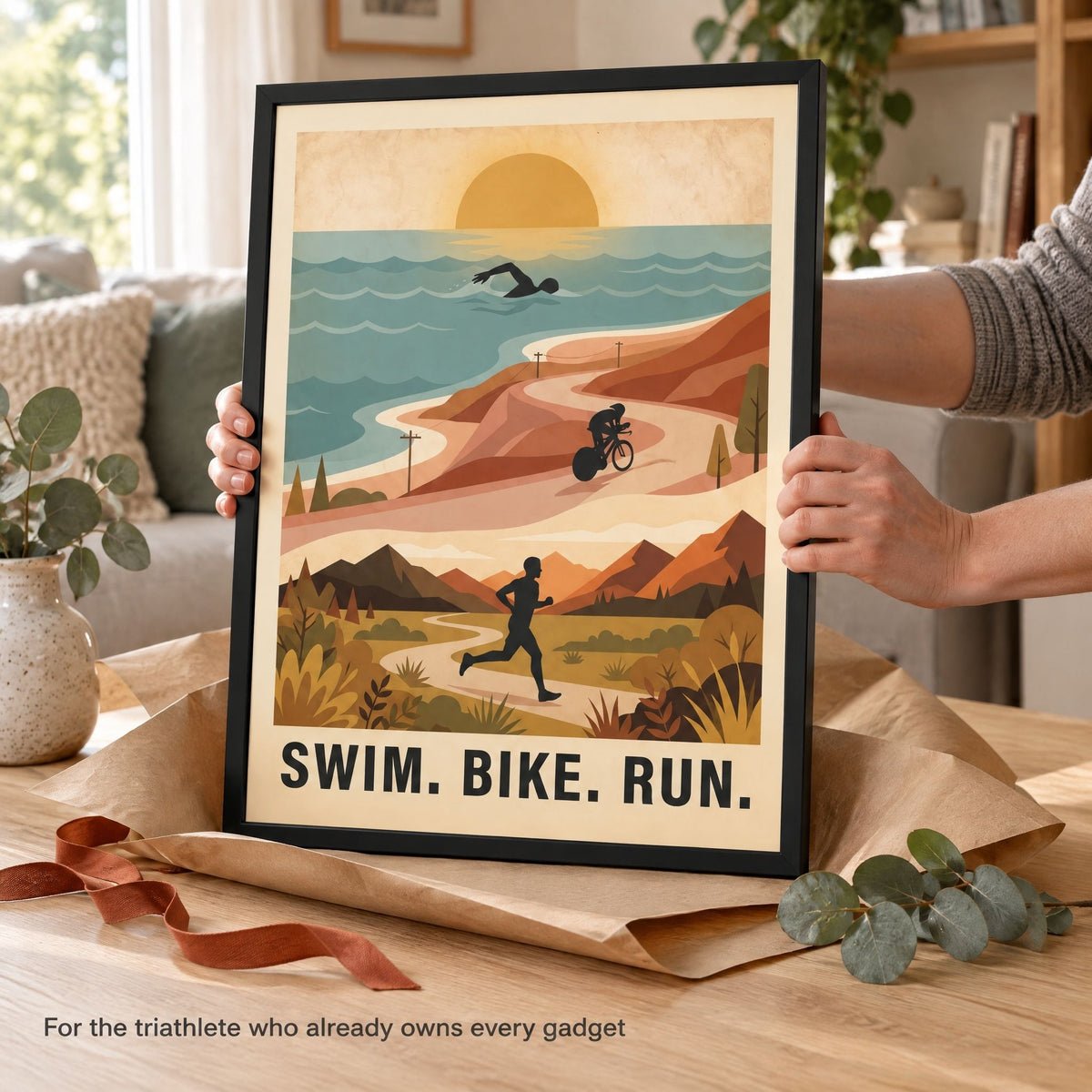 Hands steadying a framed triathlon print with its kraft wrapping peeled open, styled as a gift for an endurance athlete