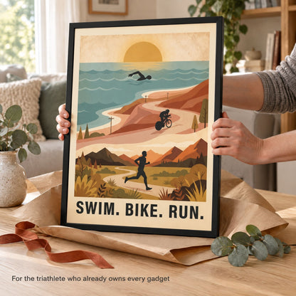 Hands steadying a framed triathlon print with its kraft wrapping peeled open, styled as a gift for an endurance athlete