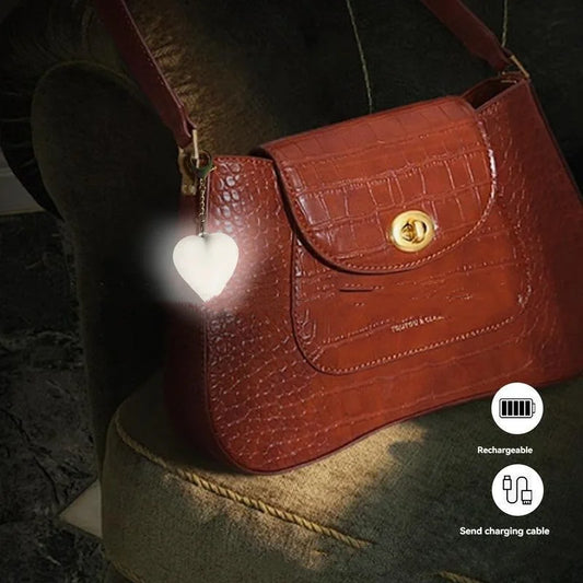 Heart-shaped rechargeable bag light attached to shoulder purse in low light