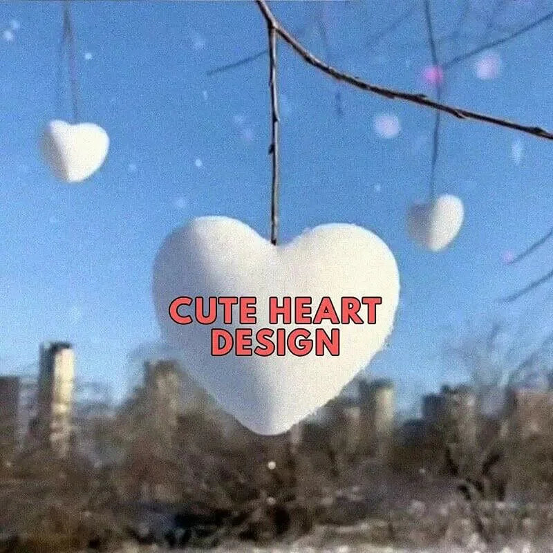 Heart-shaped snow decoration hanging from tree branch outdoors in winter setting
