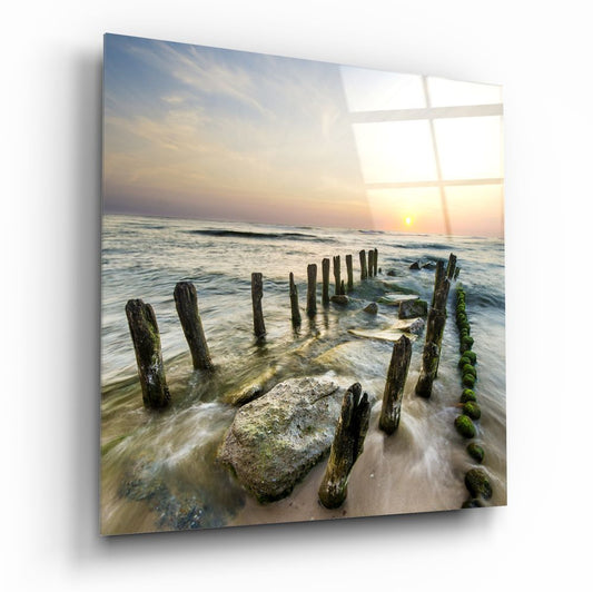 Coastal glass wall art with mossy wooden groynes and rocks in silky surf at golden hour