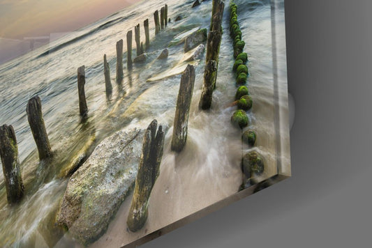 Glossy edge close-up of the sea groynes glass wall art showing mossy posts in the surf