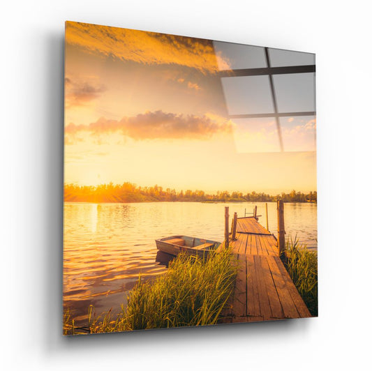 Lake glass wall art with a wooden dock, a rowboat and reeds under a golden sunset