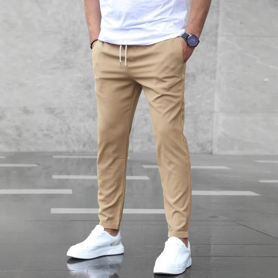 Khaki men’s modern slim-fit pants featured in a clean outdoor setting