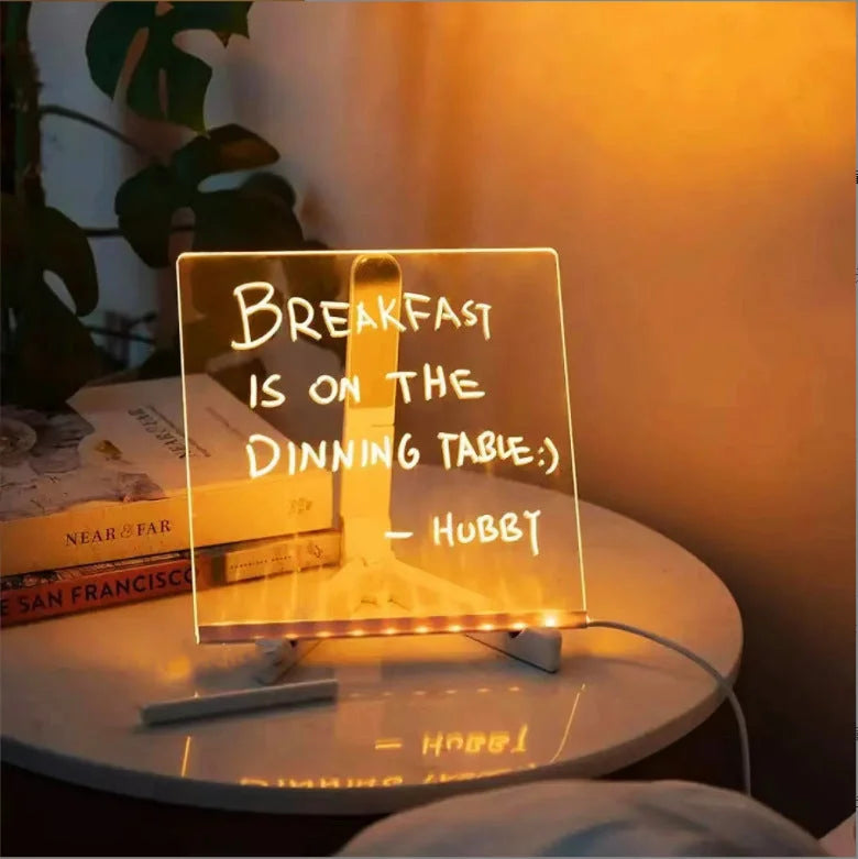 LED acrylic message board on a bedside table displaying a handwritten illuminated note.