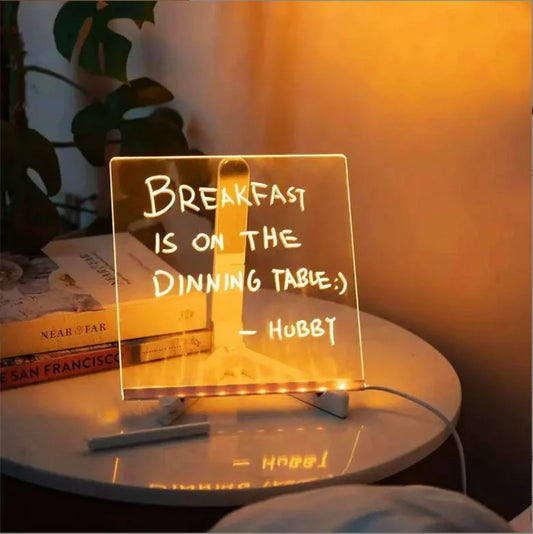 LED acrylic message board on a bedside table displaying a handwritten illuminated note.