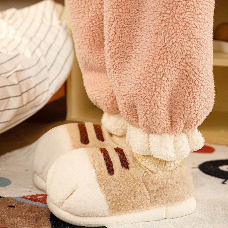 Light khaki warm velvet slippers worn indoors, showing plush material and thick cushioned soles.