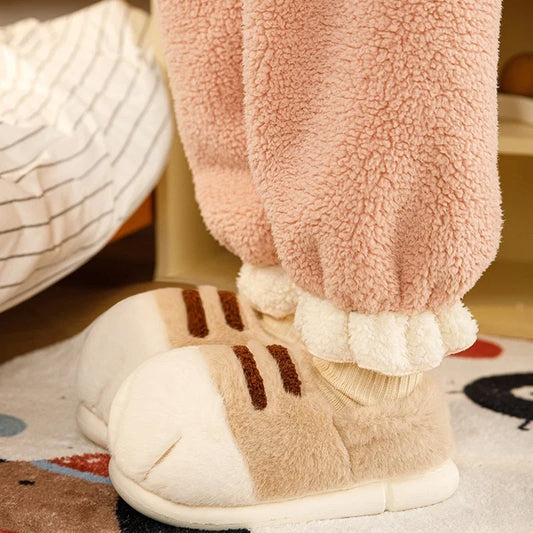 Light khaki warm velvet slippers worn indoors, showing plush material and thick cushioned soles.