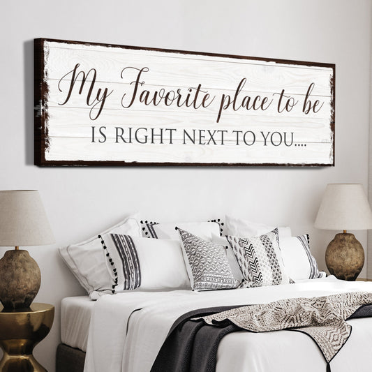 My Favorite Place to Be Is Right Next to You canvas sign in dark script on white, above a bed with patterned pillows