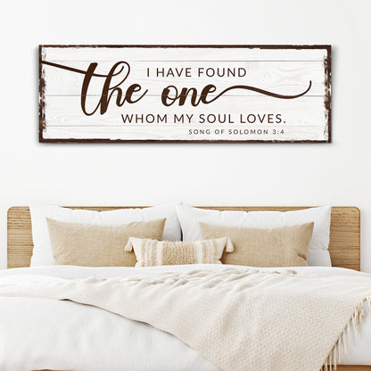 Long white wood-look canvas with brown script: I have found the one whom my soul loves, Song of Solomon 3:4, above a bed